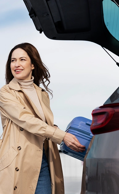 Traveler loading luggage into a rental car
